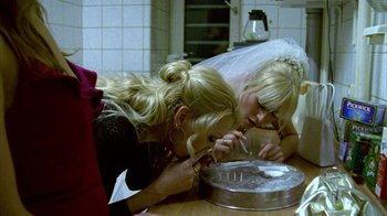 Movie still from “Pusher II” (2004), directed by Nicolas Winding Refn – Two young women are making a cake together; Medium shot, High angle