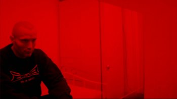 Movie still from “Pusher II” (2004), directed by Nicolas Winding Refn – A person standing in front of a red wall; Medium shot, Low angle