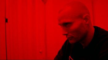 Movie still from “Pusher II” (2004), directed by Nicolas Winding Refn – A man with a bald head is looking at the camera; Close Up shot, Low angle
