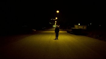 Movie still from “Pusher II” (2004), directed by Nicolas Winding Refn – A man standing in the middle of a street at night; Wide shot, Low angle