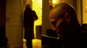 Movie still from “Pusher II” (2004), directed by Nicolas Winding Refn – A man with a bald head looking down at his cell phone; Close Up shot, Low angle