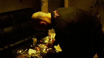 Movie still from “Pusher II” (2004), directed by Nicolas Winding Refn – A bald man is looking down at a pile of food; Medium shot, High angle