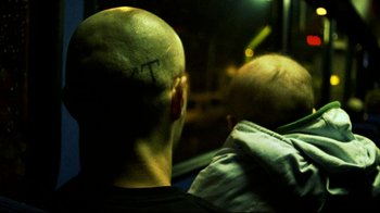 Movie still from “Pusher II” (2004), directed by Nicolas Winding Refn – A man with a bald head with a t on his head; Close Up shot, Overhead angle
