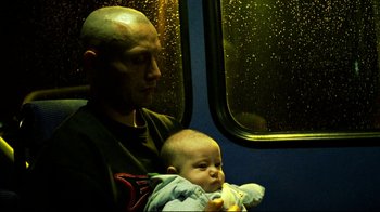 Movie still from “Pusher II” (2004), directed by Nicolas Winding Refn – A man and a baby on a train; Close Up shot, High angle
