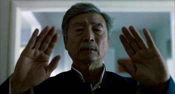 Movie still from “Pushing Hands” (1991), directed by Ang Lee – An older man with his hands raised in the air; Close Up shot, Low angle