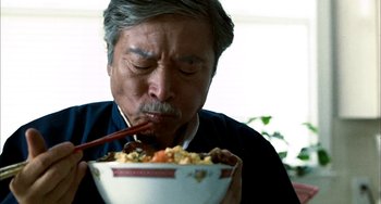 Movie still from “Pushing Hands” (1991), directed by Ang Lee – An older man eating a bowl of food with chopsticks in front of him; Close Up shot, Low angle