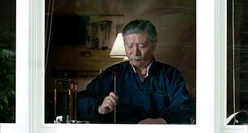 Movie still from “Pushing Hands” (1991), directed by Ang Lee – An older man holding a chopstick in his mouth; Medium shot, Low angle