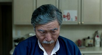 Movie still from “Pushing Hands” (1991), directed by Ang Lee – An older man with gray hair looking down at his face; Close Up shot, High angle