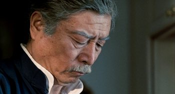 Movie still from “Pushing Hands” (1991), directed by Ang Lee – An older man with grey hair and a mustache; Close Up shot, Low angle