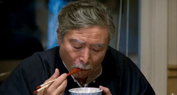Movie still from “Pushing Hands” (1991), directed by Ang Lee – An older man eating a bowl of food with chopsticks; Close Up shot, High angle