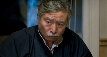 Movie still from “Pushing Hands” (1991), directed by Ang Lee – An older man sitting down with his head down; Close Up shot, High angle