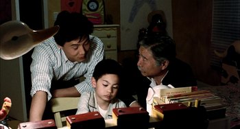 Movie still from “Pushing Hands” (1991), directed by Ang Lee – Three people sitting at a table looking at books; Medium shot, High angle