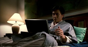 Movie still from “Pushing Hands” (1991), directed by Ang Lee – A man is sitting in bed with a laptop computer; Medium shot, Low angle