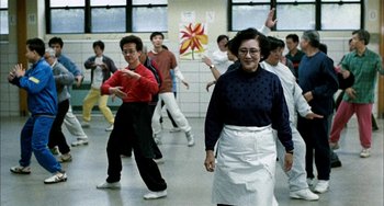 Movie still from “Pushing Hands” (1991), directed by Ang Lee – A group of people in a room doing various activities; Wide shot, Low angle