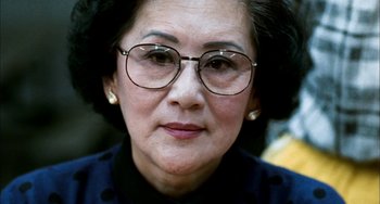 Movie still from “Pushing Hands” (1991), directed by Ang Lee – An older woman wearing glasses and a black shirt; Close Up shot, Low angle