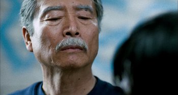 Movie still from “Pushing Hands” (1991), directed by Ang Lee – An older man with his eyes closed and his head down; Close Up shot, Over the shoulder angle