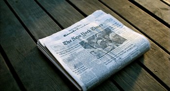 Movie still from “Pushing Hands” (1991), directed by Ang Lee – A newspaper sitting on top of a wooden table; Extreme Close Up shot, Overhead angle