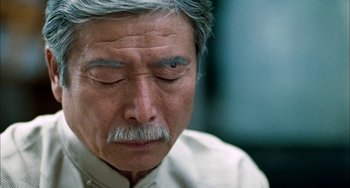 Movie still from “Pushing Hands” (1991), directed by Ang Lee – An older man with grey hair and a mustache; Close Up shot, Over the shoulder angle