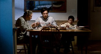 Movie still from “Pushing Hands” (1991), directed by Ang Lee – Three people sitting at a dinner table eating food; Wide shot, High angle