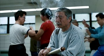 Movie still from “Pushing Hands” (1991), directed by Ang Lee – An older man smoking a cigarette while sitting in a room; Medium shot, Low angle