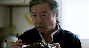 Movie still from “Pushing Hands” (1991), directed by Ang Lee – An older man holding chopsticks over a bowl of food; Close Up shot, Over the shoulder angle