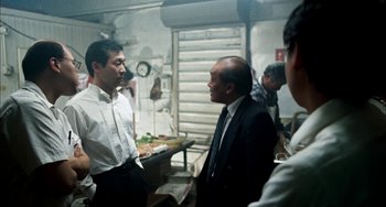 Movie still from “Pushing Hands” (1991), directed by Ang Lee – A group of men standing next to each other in a room; Medium shot, Over the shoulder angle