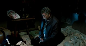Movie still from “Pushing Hands” (1991), directed by Ang Lee – A man sitting on the floor in a dark room; Medium shot, High angle