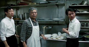 Movie still from “Pushing Hands” (1991), directed by Ang Lee – A man and a woman in a restaurant kitchen; Medium shot, High angle
