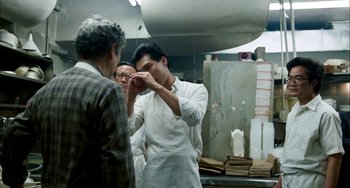 Movie still from “Pushing Hands” (1991), directed by Ang Lee – A man in a white shirt is putting something on another man's face; Medium shot, Over the shoulder angle