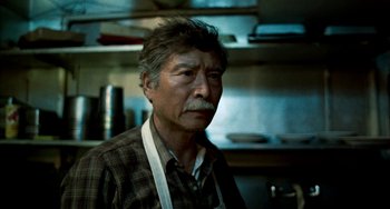 Movie still from “Pushing Hands” (1991), directed by Ang Lee – An older man wearing a plaid shirt in a kitchen; Close Up shot, Low angle
