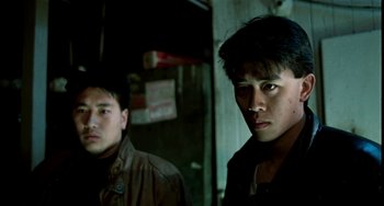 Movie still from “Pushing Hands” (1991), directed by Ang Lee – Two asian men standing next to each other in a dark room; Close Up shot, Low angle