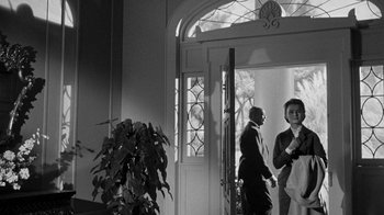 Movie still from “Queen Bee” (1955), directed by Ranald MacDougall – Two people standing in front of an open door; Wide shot, Low angle