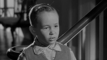 Movie still from “Queen Bee” (1955), directed by Ranald MacDougall – A young boy wearing a bow tie and a plaid shirt; Close Up shot, Over the shoulder angle
