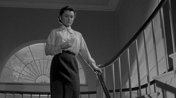 Movie still from “Queen Bee” (1955), directed by Ranald MacDougall – A black and white photo of a woman standing on the stairs; Medium shot, Low angle