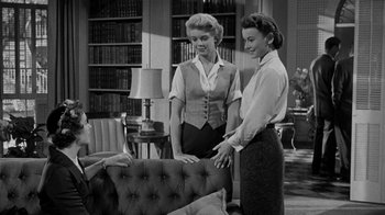 Movie still from “Queen Bee” (1955), directed by Ranald MacDougall – Two women are standing next to each other in front of a couch; Medium shot, High angle