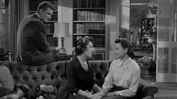 Movie still from “Queen Bee” (1955), directed by Ranald MacDougall – Two women and a man sitting on a couch in front of a bookcase; Medium shot, Over the shoulder angle