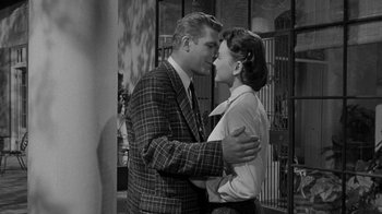 Movie still from “Queen Bee” (1955), directed by Ranald MacDougall – A man and a woman are kissing in a room; Medium shot, High angle