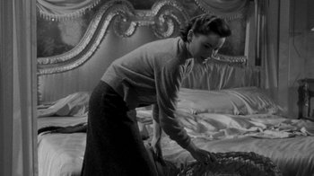 Movie still from “Queen Bee” (1955), directed by Ranald MacDougall – A black and white photo of a woman putting a blanket on a bed; Medium shot, High angle