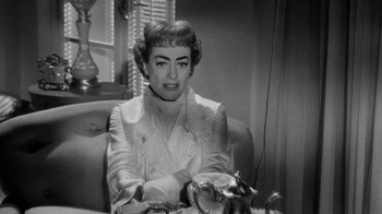 Movie still from “Queen Bee” (1955), directed by Ranald MacDougall – A black and white photo of a woman sitting at a table; Close Up shot, High angle
