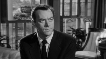 Movie still from “Queen Bee” (1955), directed by Ranald MacDougall – A man wearing a suit and tie sitting in front of a window; Close Up shot, Over the shoulder angle
