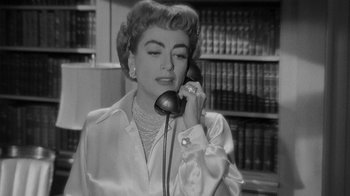 Movie still from “Queen Bee” (1955), directed by Ranald MacDougall – An older woman talking on a phone in a library; Close Up shot, High angle