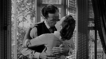 Movie still from “Queen Bee” (1955), directed by Ranald MacDougall – A man and a woman embracing in front of a window; Medium shot, Low angle
