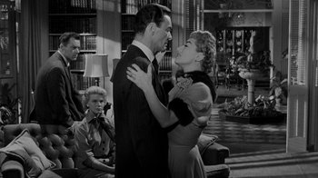 Movie still from “Queen Bee” (1955), directed by Ranald MacDougall – A man and a woman are kissing in front of a crowd; Medium shot, Over the shoulder angle