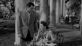 Movie still from “Queen Bee” (1955), directed by Ranald MacDougall – A man and a woman sitting at an outdoor table; Medium shot, High angle