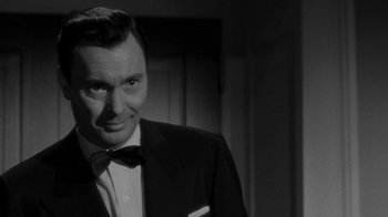 Movie still from “Queen Bee” (1955), directed by Ranald MacDougall – A black and white photo of a man in a suit and bow tie; Close Up shot, Over the shoulder angle