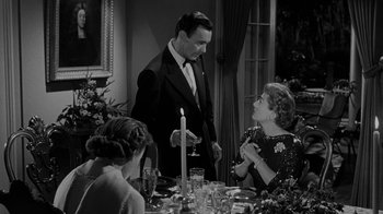 Movie still from “Queen Bee” (1955), directed by Ranald MacDougall – A man and a woman standing in front of a dinner table; Medium shot, Over the shoulder angle