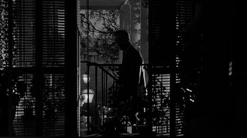 Movie still from “Queen Bee” (1955), directed by Ranald MacDougall – A man standing on a porch with a railing; Wide shot, Low angle