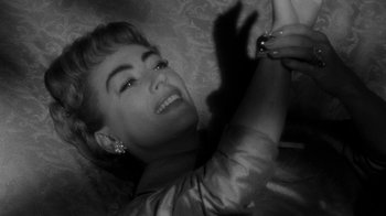 Movie still from “Queen Bee” (1955), directed by Ranald MacDougall – A black - and - white photo of a woman smiling for the camera; Close Up shot, Overhead angle