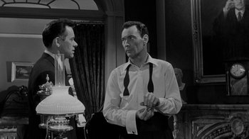 Movie still from “Queen Bee” (1955), directed by Ranald MacDougall – A man in a white dress shirt and black tie standing next to another man in a white dress shirt and black tie; Medium shot, Over the shoulder angle