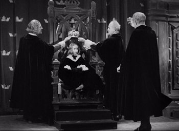 Movie still from “Queen Christina” (1933), directed by Rouben Mamoulian – A woman sitting on a throne surrounded by four judges; Wide shot, High angle